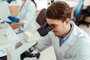 Wall Mural - nice handsome biologist using a professional microscope
