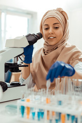 Wall Mural - positive muslim woman studying test samples in the lab