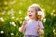 © Irina Schmidt - Adorable cute little baby girl blowing on a dandelion flower on the nature in the summer. Happy healthy beautiful toddler child with blowball, having fun. Bright sunset light, active kid.