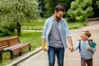 © Iryna - Parent take child to school. Pupil of primary school go study with backpack outdoors. Father and son go hand in hand. Beginning of lessons. Back to school. First day of fall. Elementary student.