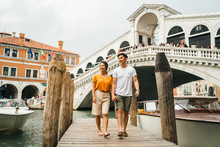 Loving Couple On Vacation In Venice, Italy - Millennials Visiting The Famous Rialto Bridge While Walking On The Wooden Pier