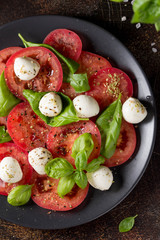 Canvas Print - Caprese salad with mini mozzarella, juicy tomato and fresh Basil. Delicious Italian snack, traditional food. On dark background