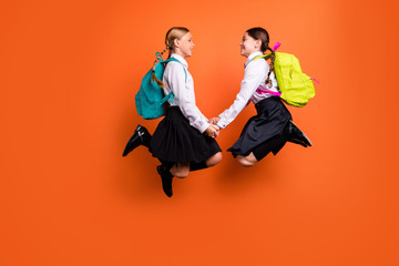 Wall Mural - Full length body size profile side view of two person nice attractive charming friendly cheerful cheery pre-teen girls having fun time holding hands isolated on bright vivid shine orange background