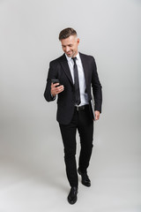 Wall Mural - photo of happy adult businessman in formal suit smiling while holding laptop and cellphone