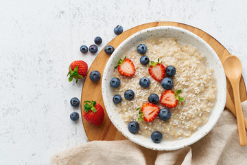 Wall Mural - Oatmeal porridge rustic with berries, dash diet, on white wooden background top view