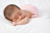 Fototapeta Niebo - Adorable asian newborn baby in pink wrap sleeping on white blanket background.