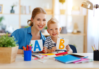 Wall Mural - mother and child son doing homework writing and reading at home.