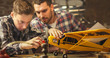 © Gorodenkoff - Father and son are modeling a toy airplane in a garage at home.