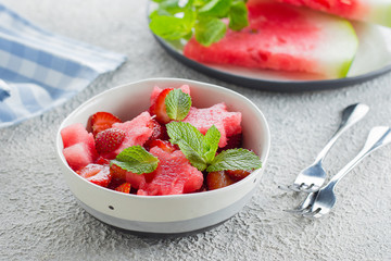 Wall Mural - Summer salad with watermelon and strawberry on concrete background table, close-up