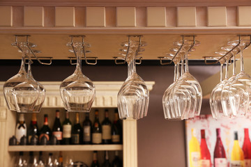 Set of empty clean glasses on bar racks