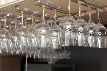 Set of empty clean glasses on bar racks