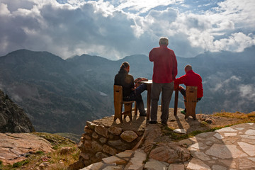 Wall Mural - Three hikers contemplate the alpine panorama outside a mountain hut.