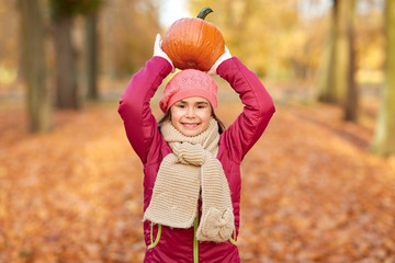 Sticker - childhood, season and people concept - happy girl with pumpkin at autumn park