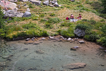 Wall Mural - a couple of tourists on the shores of an alpine lake.