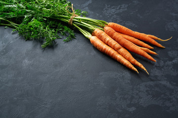 Bunch of fresh carrots on black background, with copy space.