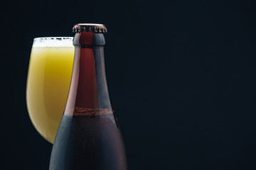 Poster - Close up Glass of beerand brown Bottle on a dark background behaid.