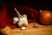 Garlic And Onion On Wooden Background With Red Jute Sack