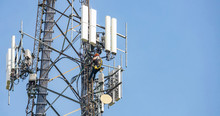 Telecom Maintenance. Man Climber On Tower Against Blue Sky Background
