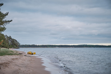 Wall Mural - yellow pedal boat floating ashore up and down the beach, dark clouds on the sky and beach in the foreground