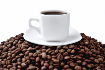 Wall Mural - white cup of coffee on a white saucer stands on a hill of coffee beans on a white background