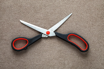 Close-up of sharp steel metal scissors isolated on light cloth copy space background. Household equipment, office or school tools.