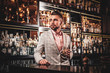 © Fxquadro - Handsome modern man in checkered suit is consuming alcohol at trendy bar.