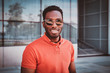 © Fxquadro - Portrait of happy smiling afro student in sunglasses over glass building.