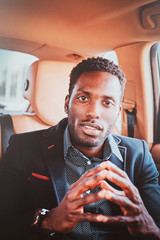 Wall Mural - Portrait of pensive elegant afro etnicity businessman in the car as a passenger.