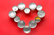Heart shape made of tin cans with food on color background