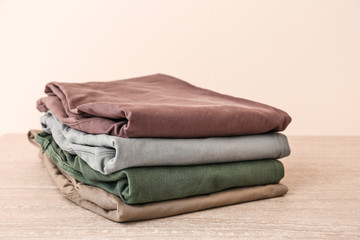 Stack of clean clothes on table against light background