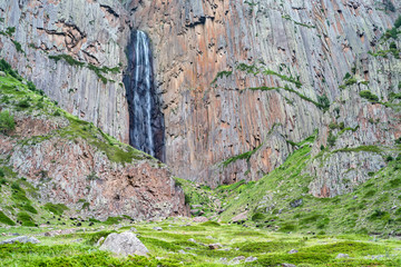 Summer landscape with mountain waterfall between two rocks