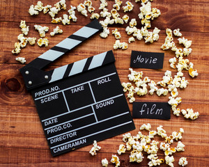Clapperboard and popcorn on wooden background