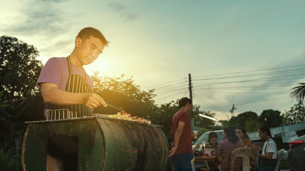 Wall Mural - BBQ party group of people at barbecue dinner friends having food together outdoor as summer with friendship asian person.