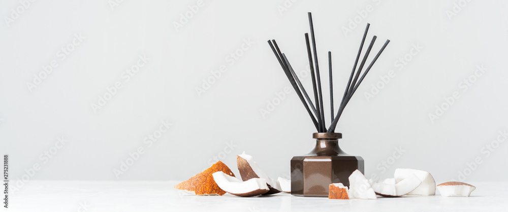 Aroma reed diffuser bottle home fragrance with rattan sticks with the scent of coconut and the freshness of the tropics on white background. Long wide banner with copy space. - obrazy, fototapety, plakaty 