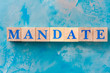 Wooden cubes with word MANDATE on blue table.