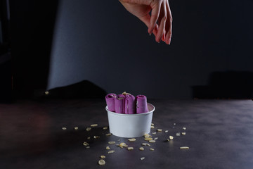 Hand sprinkles almond chips on purple thai rolled ice cream