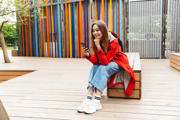 Wall Mural - Cheerful attractive young girl wearing raincoat