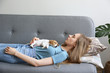 © Evrymmnt - The cuttest two months old Jack Russel terrier puppy named Maisie sleeping on young woman's chest. Small adorable doggy w/ funny fur stains resting with owner on couch. Close up, copy space background