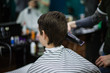 © Dima - A young successful hairdresser, making an attractive man's haircut in a hairdresser. to cut long hair. man's haircut