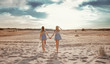 © Maksym - Two girls walk along the sand against the sky in the sunset