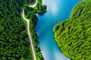 Aerial view over beautiful turquoise mountain lake and green forest. Spring in the mountains. Green forest, mountain lake. Green pine and fir trees forest and a lake. Beautiful mountain road. - Image