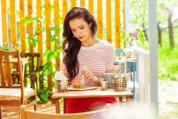 Beautiful woman eating alone in a summer cafe.