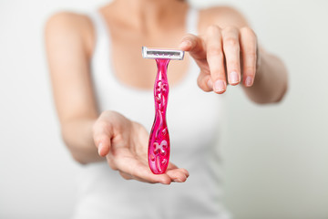 Pink razor between two hands of young woman