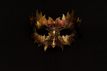 Venetian mask in gold and red with metallic pieces in the form of leaves. original and unique design, handmade crafts