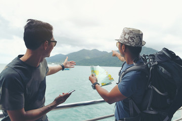 Two young travelers are planning a tour by looking at the map and searching on the smartphone.