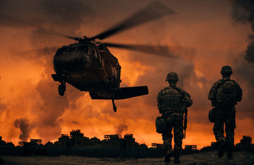 Military soldiers walking to helicopter in battlefield at sunset