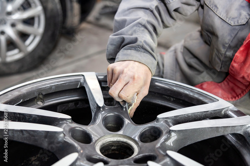 Fotografía Master body repair man is working on preparing the surface of the aluminum wheel