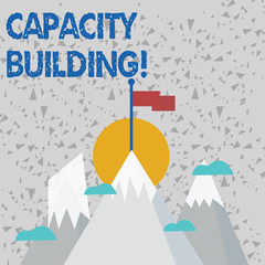Text sign showing Capacity Building. Business photo text Strengthen the abilities of individuals Workforce planning Three High Mountains with Snow and One has Blank Colorful Flag at the Peak