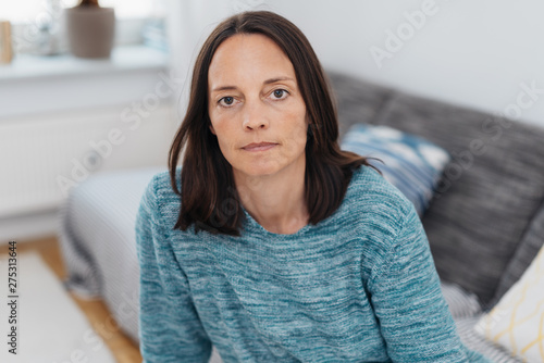 Fotomural ernste Frau sitzt auf dem sofa und schaut in die kamera