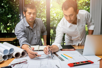 Engineer or architect meeting for project working with partner and using divider compass tools on blueprint in office on site.